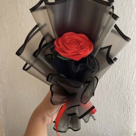 Rosa roja de listón satinado envuelta en papel negro con moño rojo